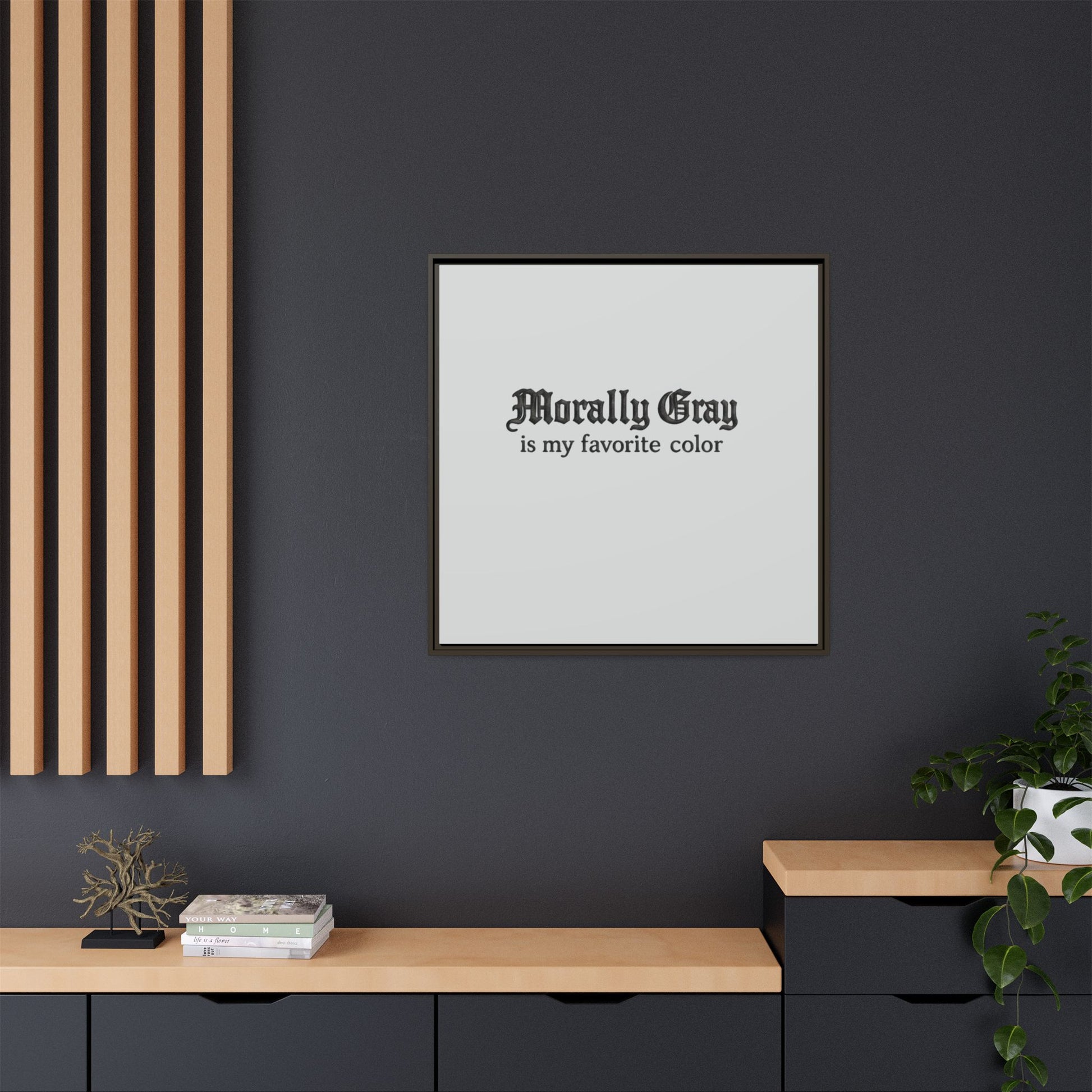 Minimalist framed wall art with the phrase "Morally Gray is my favorite color" displayed in black gothic font on a white background, styled in a modern living space with dark gray walls, wooden accents, and green plants, showcasing the Unknown Product.