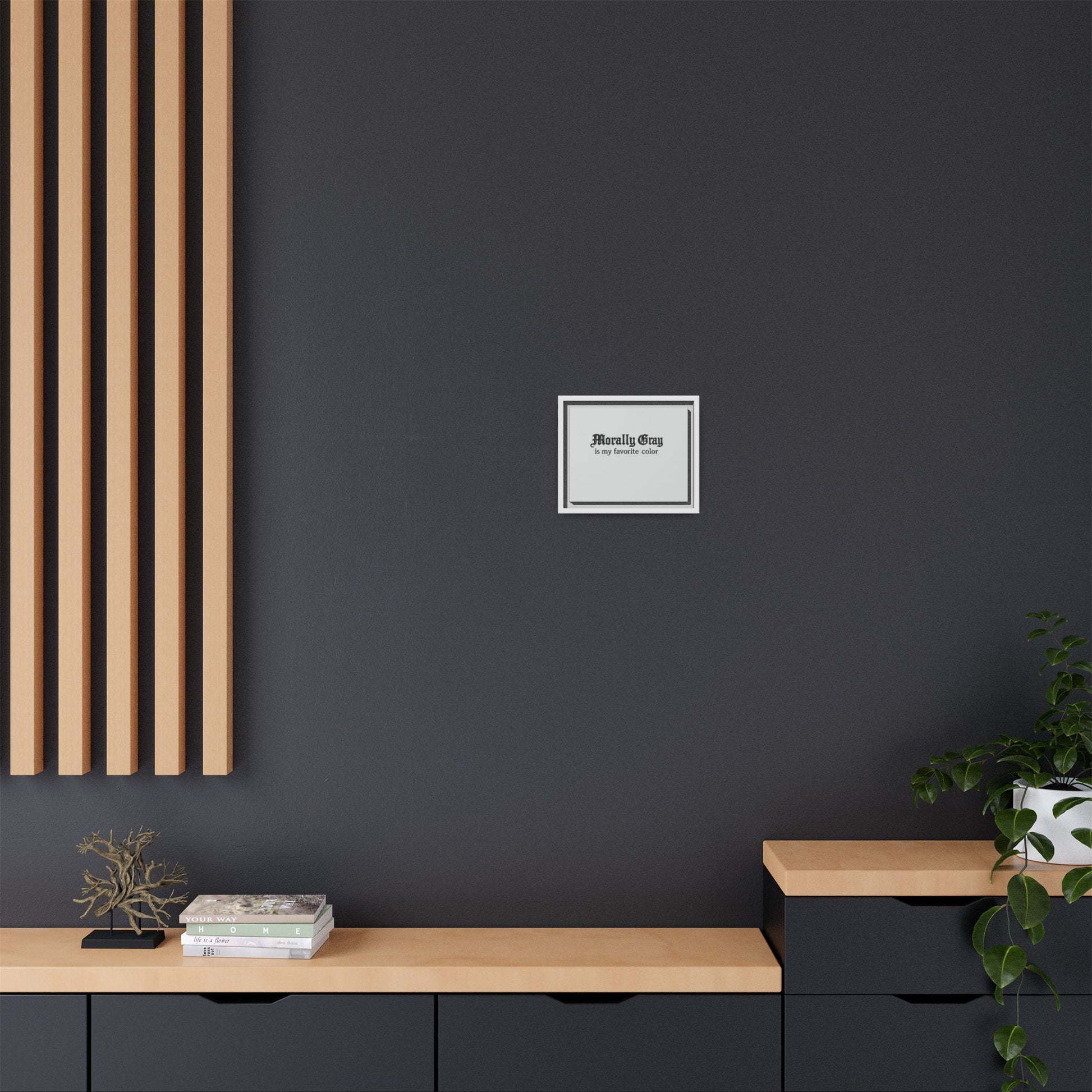 Minimalist modern interior with dark gray wall featuring a small framed print reading Morally Gray, light wood shelves, black cabinetry, and a green potted plant, Unknown Product.