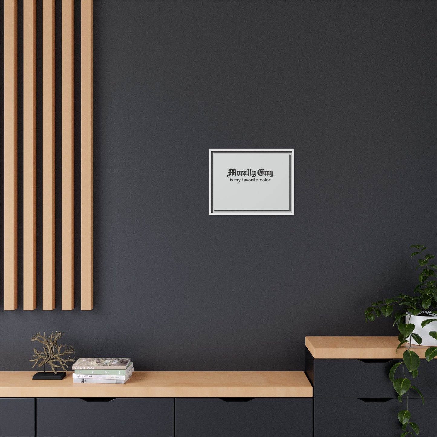 Minimalist interior with a dark gray wall featuring a framed sign that reads "Morally Gray is my favorite color," styled with wood accents and a small plant, showcasing Unknown Product.